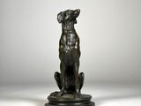 une statue en bronze représentant un chien assis sur un socle