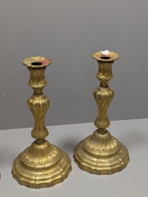 trois bougeoirs en laiton posés sur une table blanche, sur fond gris