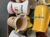 une boîte remplie de tasses à café et de mugs posée par terre