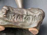 a bronze sculpture of a dog on a rock with a cone in the background