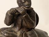 a bronze statue of a boy sitting on a rock