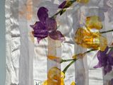 des fleurs violettes et jaunes sur un rideau en voile accroché à un mur