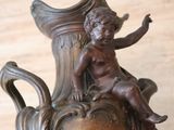 a bronze statue of a boy sitting on a vase