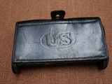 un portefeuille en cuir orné du logo « us », posé sur une surface marron