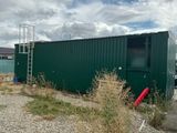 a green container sitting in the middle of a gravel lot