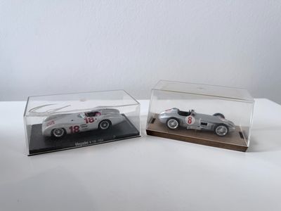 deux modèles réduits de voitures exposés dans des vitrines posées sur une table