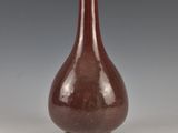 un vieux vase marron posé sur une table près d'un mur gris