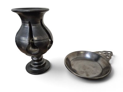 un vase en argent à côté d'une cuillère en argent, posé sur une surface blanche