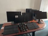 a lot of computer monitors and keyboards on the desk