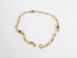 un bracelet en or orné de grenats et de pierres sur fond blanc