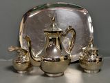 a silver plate with a silver tea pot and two silver cups on it