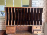 a wooden desk with drawers and a mirror on the wall