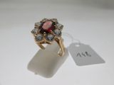 un gros plan d'une bague ornée d'une pierre rouge entourée de pierres blanches