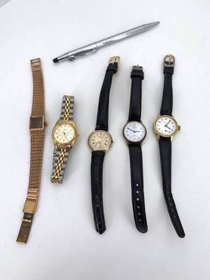 five watches and a pen on a table