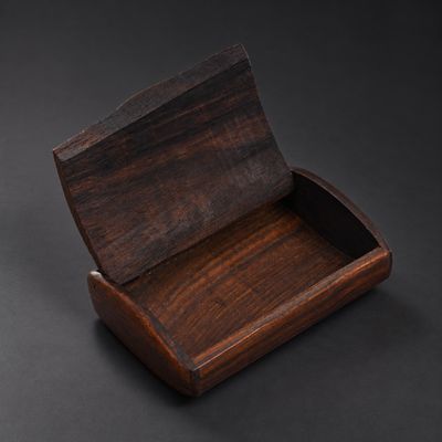 une boîte en bois vide posée sur une surface noire, avec un fond noir