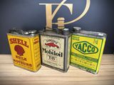 three old oil cans are sitting on a table next to each other