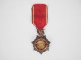 gros plan d'une médaille sur une surface blanche avec un ruban rouge