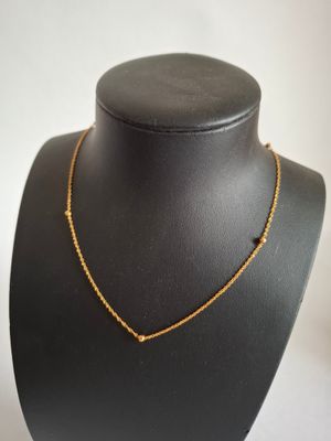 a black mannequin with a gold necklace on it