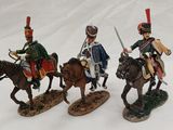 three figurines of soldiers riding on horses on a white surface