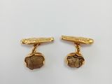 a pair of gold plated cufflinks with a picture of a man and a woman