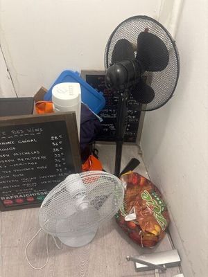 a fan sitting next to a table with a sign on it