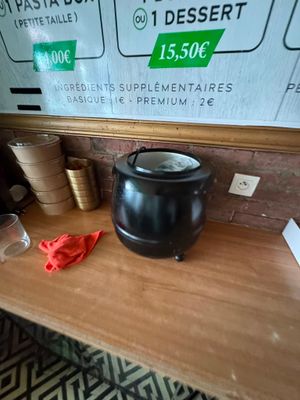 une cafetière noire posée sur une table en bois, à côté d'une tasse de café
