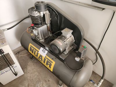 un petit compresseur d'air posé par terre à côté d'un radiateur
