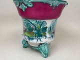 a purple and green planter sitting on a white table