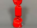 un vase rouge posé sur un socle transparent