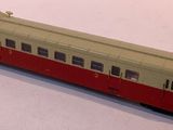 a red and white train on the tracks on a white surface