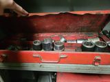 a red tool box with tools in it and a hand reaching for it