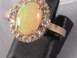 a close up of an oplite and diamond ring on a black surface