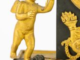 a gold statue of a boy with a clock on a table
