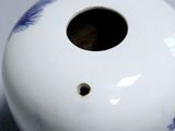 a white vase with blue flowers on it sitting on a table