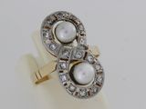 une photo d'une bague en perle blanche et diamants posée sur une surface blanche
