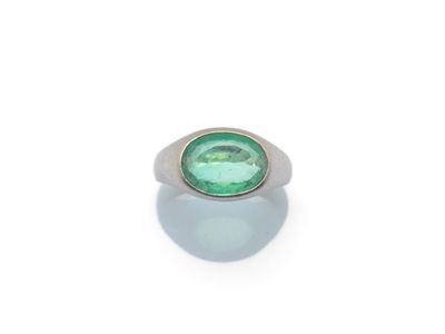un gros plan d'une bague ornée d'une pierre verte sur un fond blanc