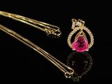 a gold necklace with a pink stone and a gold chain