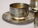 a silver cup and saucer sitting on a saucer
