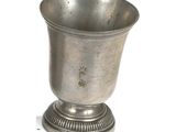a silver cup sitting on a pedestal on a white surface