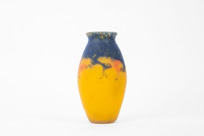 un vase jaune et bleu posé sur une surface blanche