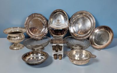 silver plated dishes and bowls on a table with a blue wall in the background