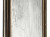 un miroir avec un cadre noir et des finitions dorées sur un mur blanc