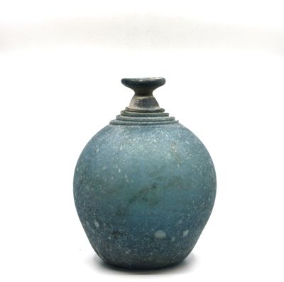 un vase bleu posé sur une surface blanche