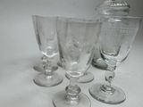 four wine glasses sitting on a table next to a bottle