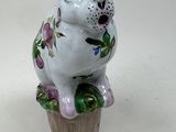 a figurine of a dog sitting on top of a flower pot