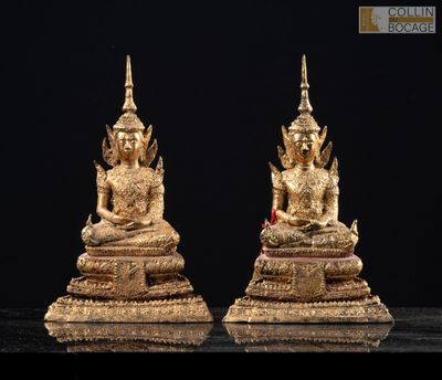 deux statues en or représentant des bouddhas assis sur un socle noir