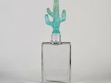 un petit cactus en verre posé sur un bloc de verre transparent