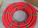 a close up of a red hose on the ground with boxes in the background