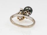 an image of a black pearl and diamond ring on a white surface