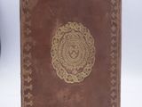 an old brown book with a gold medallion on the cover